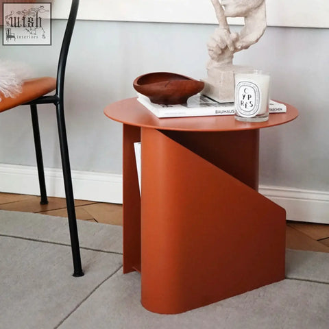 A sleek terracotta hector side table with modern geometric design painted steel and built in book storage