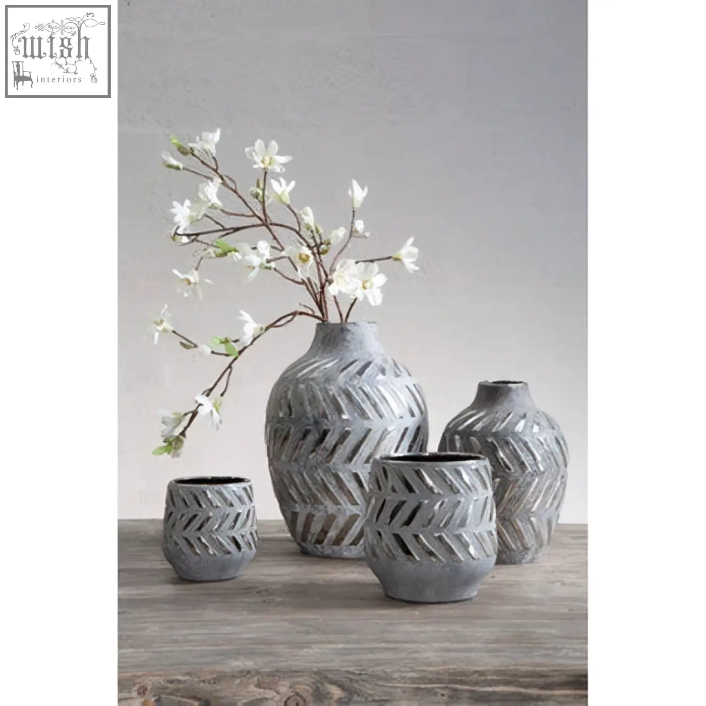 Set of four gray ceramic vases with geometric cutouts arranged on wood perfect as silver small planter decor