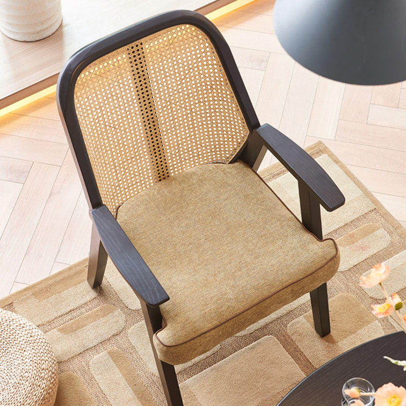 A sleek hellen rattan dining chair with black frame, woven cane back, and tan cotton linen seat upholstery