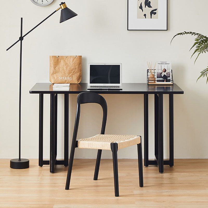 Black henry dining chair with rattan woven seat paired with sleek black desk featuring minimalist metal legs