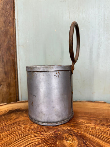 A weathered cylindrical metal herb plant pot with a rusted circular handle for desk tidy or cutlery holder use