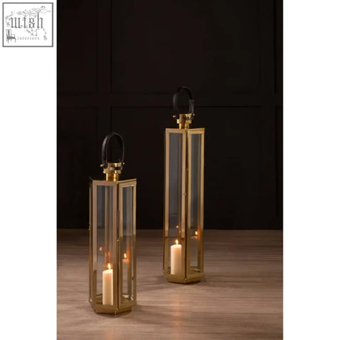 Herber large gold finish lanterns with clear glass panels, lit candles inside, and black leather handles