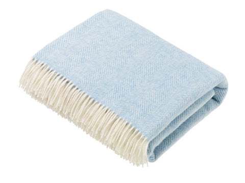 A soft light blue herringbone merino lambswool throw with cream fringe perfect for cozying up at home