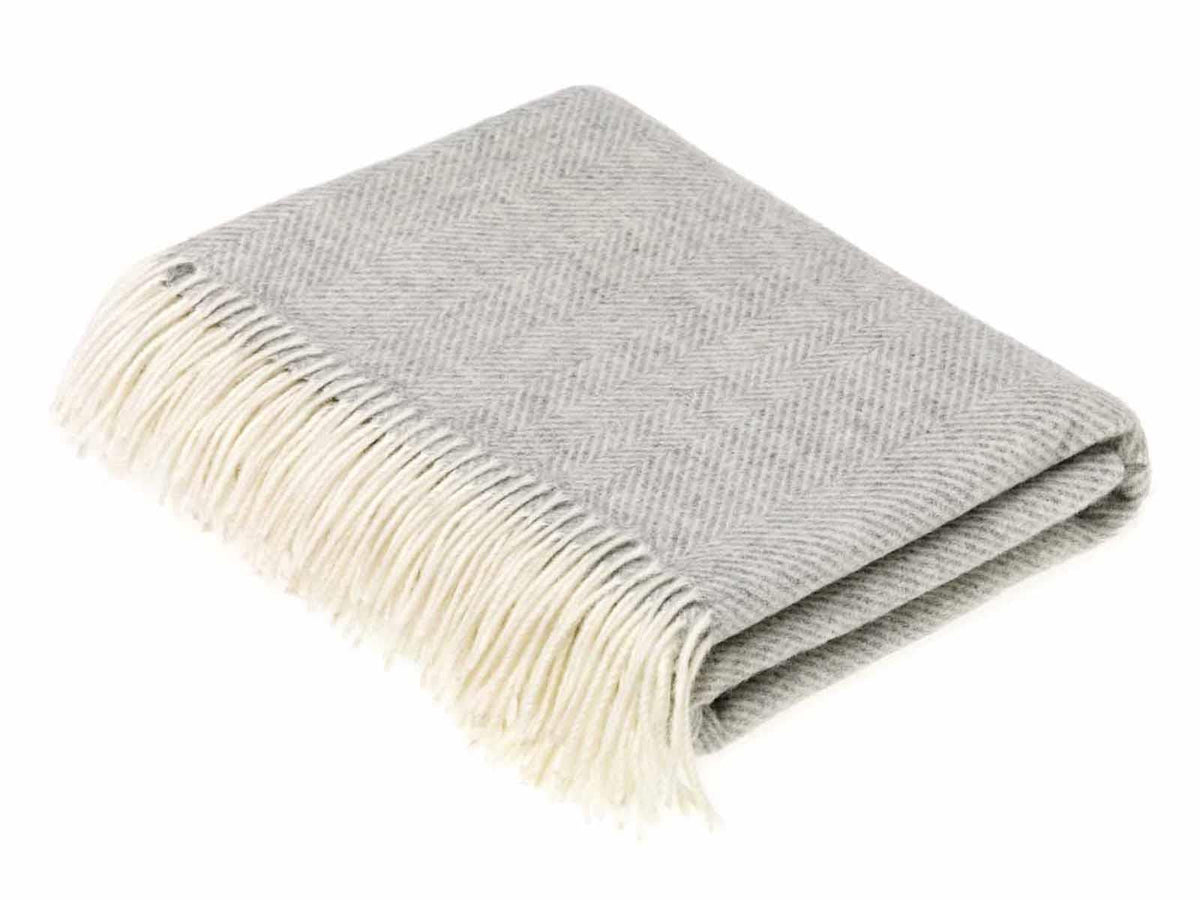 A soft grey merino lambswool throw with herringbone pattern and cream fringe perfect for cozying up