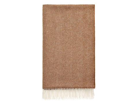 A warm rust herringbone merino lambswool throw with a soft cream fringe perfect for cozying up