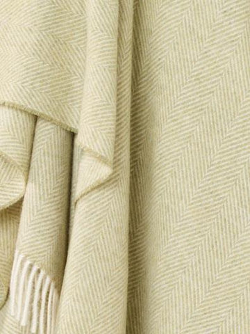 A soft cream-colored merino lambswool herringbone throw with delicate fringe in sage for cozy warmth