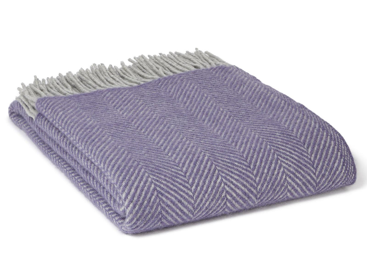 A soft herringbone pure new wool throw blanket in lavender silver with light gray fringe perfect for cozying up