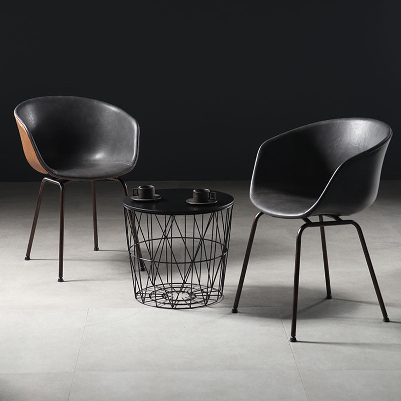 Modern black leather herron dining chairs with sleek metal legs paired with a geometric wireframe coffee table