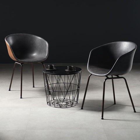Modern black leather herron dining chairs with sleek metal legs paired with a geometric wireframe coffee table