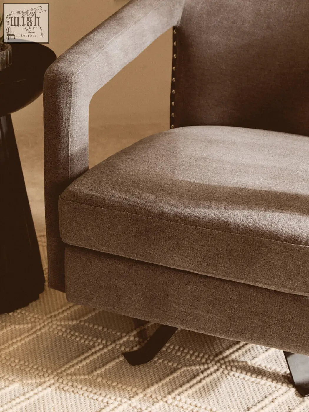 A cozy gray hestia ash velvet swivel chair with textured fabric and dark metal nailhead trim on the backrest