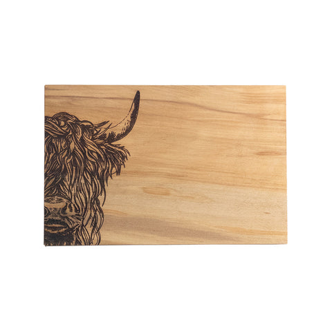 Light-colored beech serving board with detailed black-burned highland cow illustration on the left side