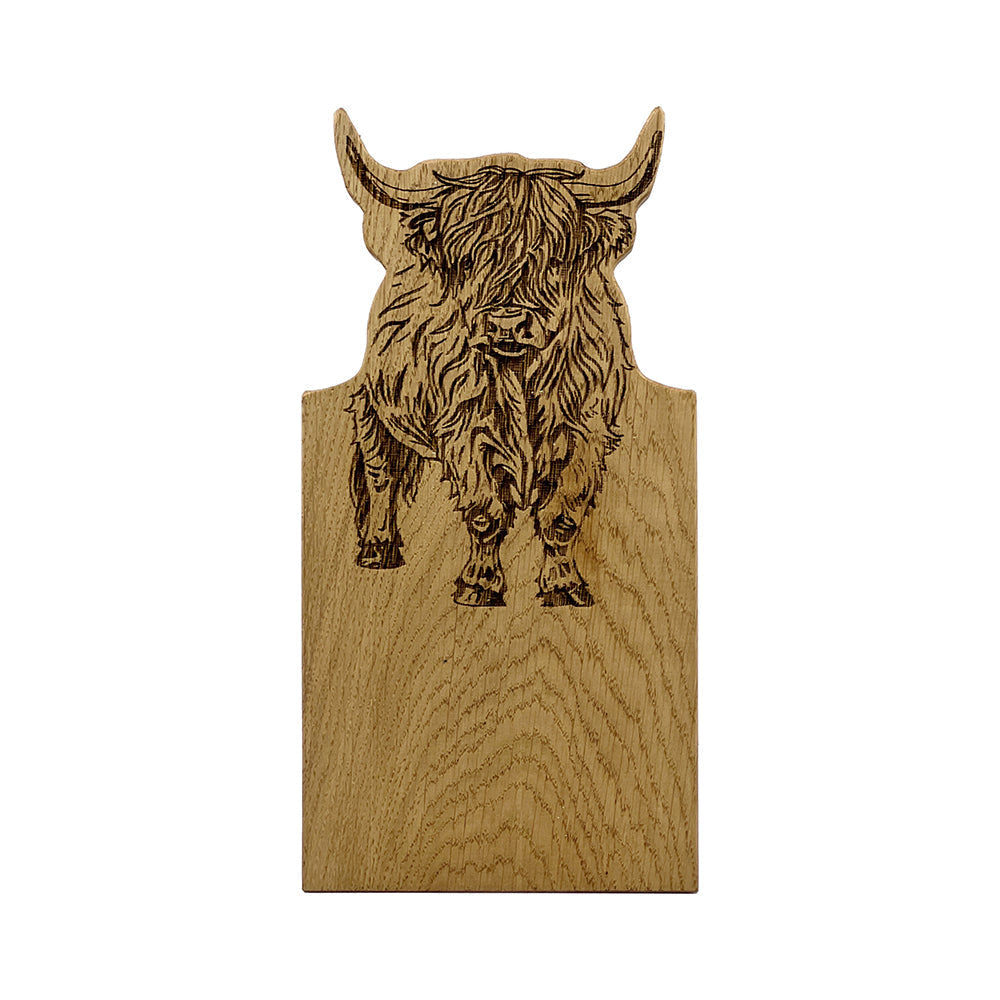 A small light oak serving board with a framed oak design featuring an engraved highland cow with shaggy fur