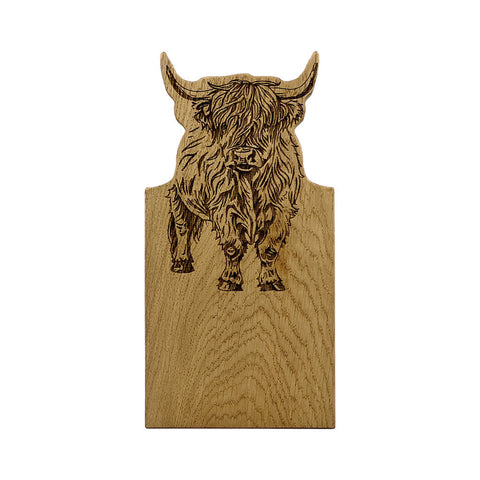 A small light oak serving board with a framed oak design featuring an engraved highland cow with shaggy fur