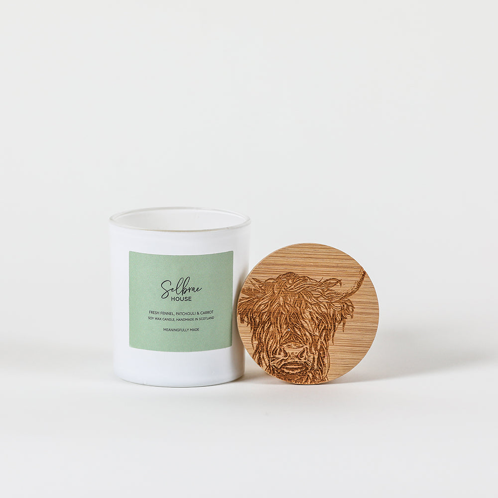 White ceramic soy wax candle jar with fresh fennel label and wooden lid engraved with highland cow design