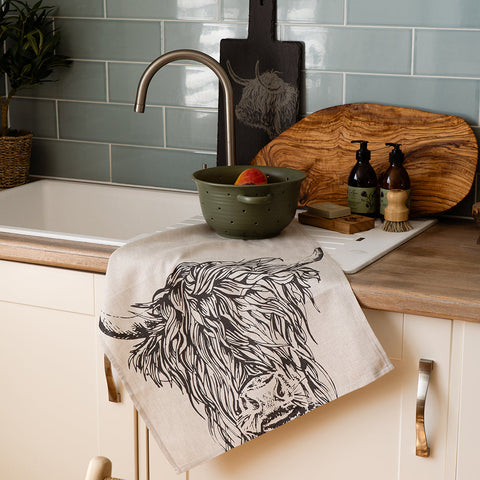 Beige linen tea towel with bold black line art of a highland cow perfect for kitchen use