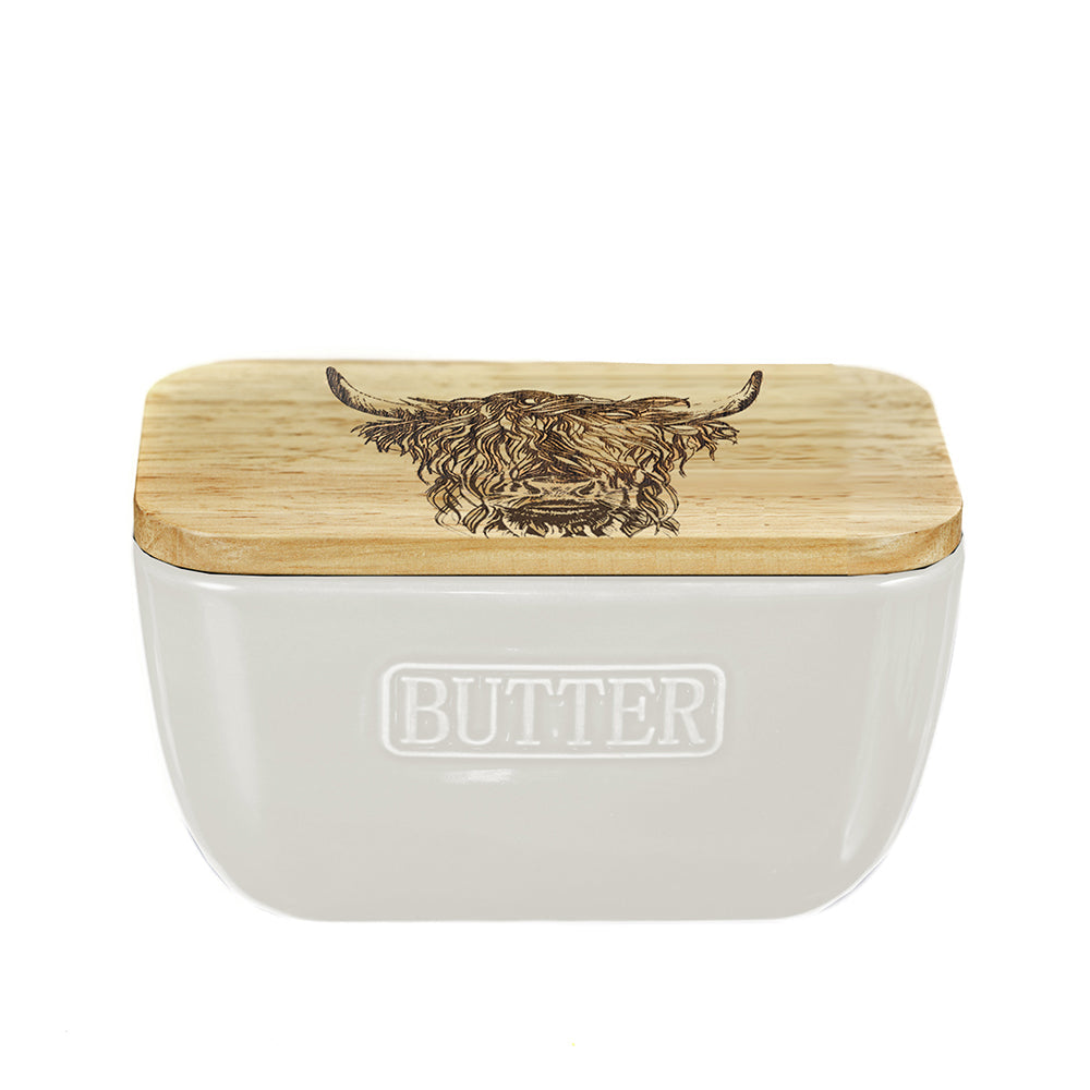 Cream-colored ceramic butter dish with natural wood lid engraved highland cow design and butter embossed on front