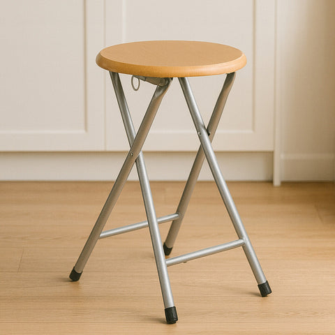 Hinata folding stool with wood veneer seat featuring a light wood-toned round top and silver metal legs with black caps