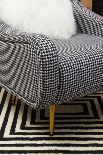 A sleek holli black and white checked armchair with gold finish legs and a classic houndstooth pattern upholstery