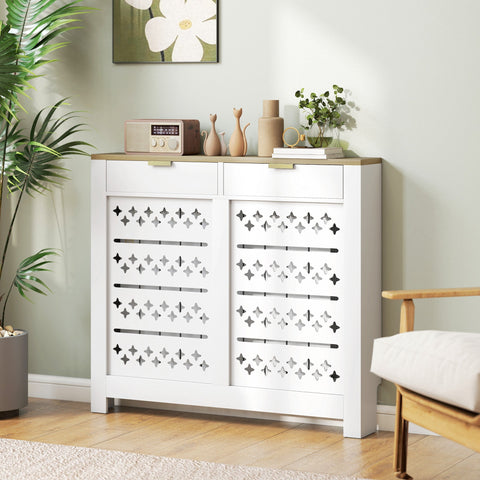 White shoe cabinet with a particle board white body, light wood top, decorative diamond cross cut-outs, and 2 drawers