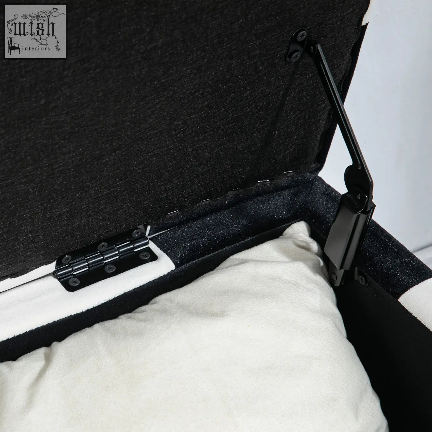 Black velvet storage ottoman with white cushion inside black metal hinges colour block design and wooden legs