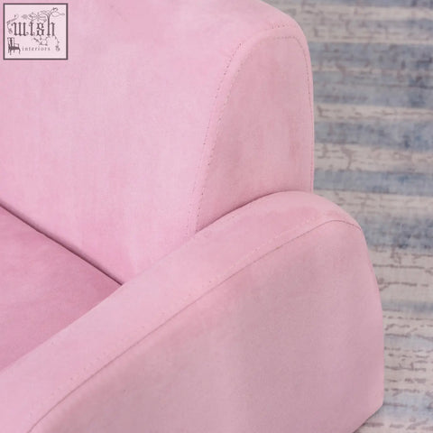Soft pink suede kids armchair with wood frame and subtle stitching doubles as a sofa bed for playroom or bedroom