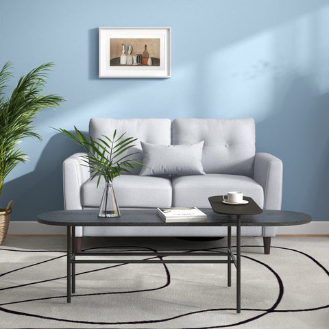 Modern black coffee table with sleek oval top and minimalist metal legs perfect for living room with seater sofa and linen upholstery