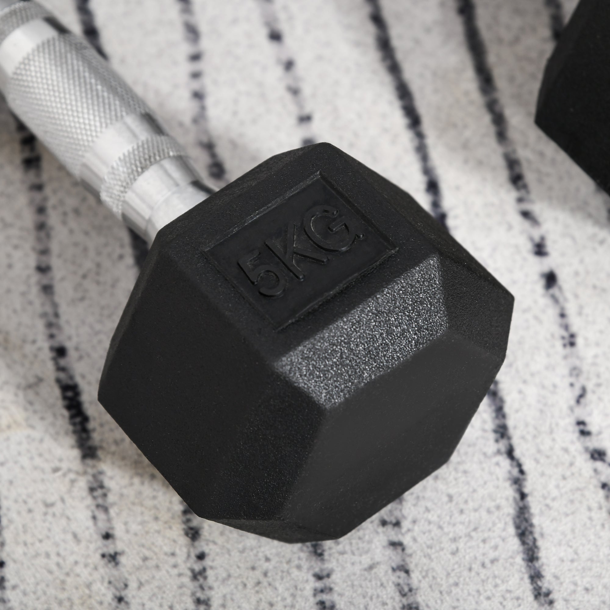 Black hexagonal rubber dumbbell with silver textured handle and 5kg engraving from homcom 2x5kg gym set