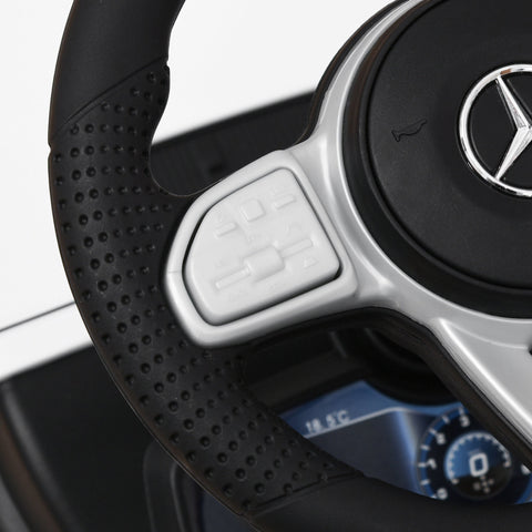 Black perforated steering wheel with silver accents and mercedes-benz logo on white homcom 3 in 1 kids ride on car with foot-to-floor design and under-seat storage