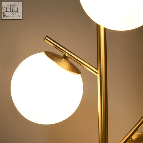 Modern gold tone floor lamp with two glowing globe shades and steel base featuring e27 base and foot switch