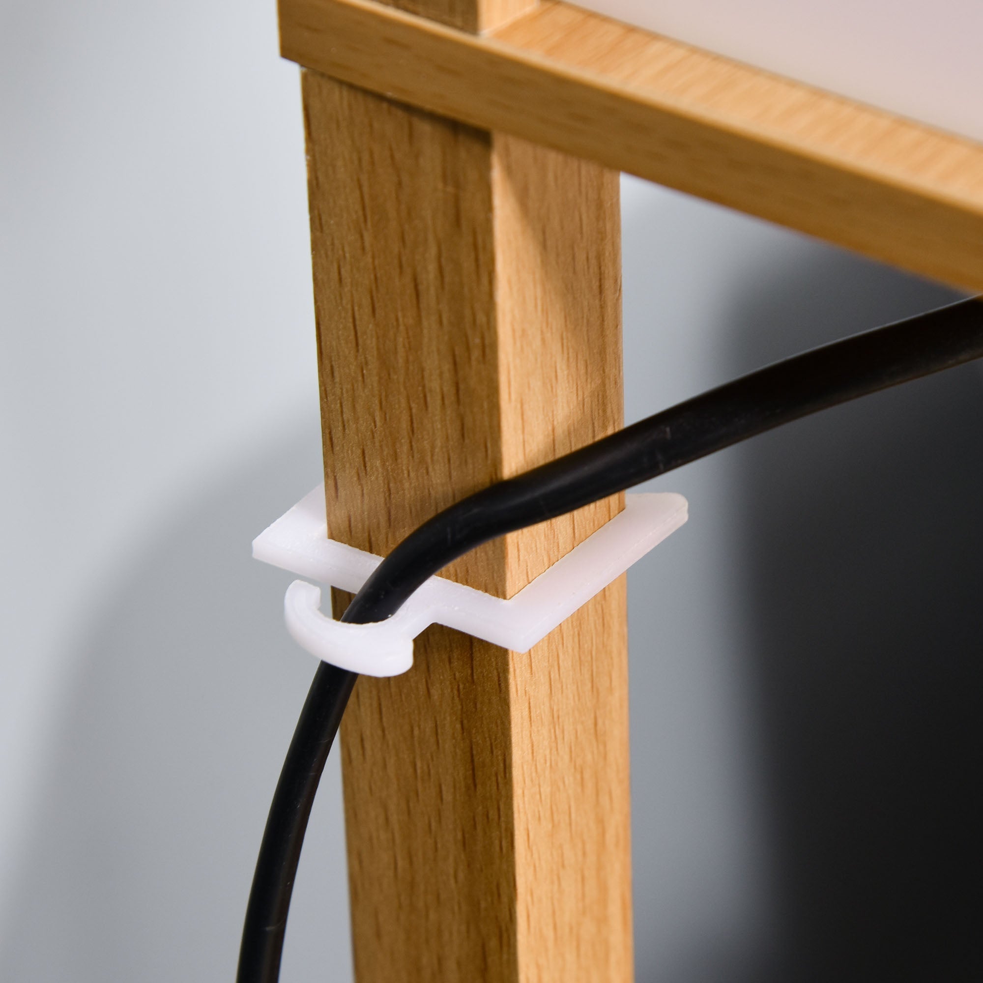 White plastic cable tie securing black cord to wooden post of homcom natural 3-tier floor lamp for living room