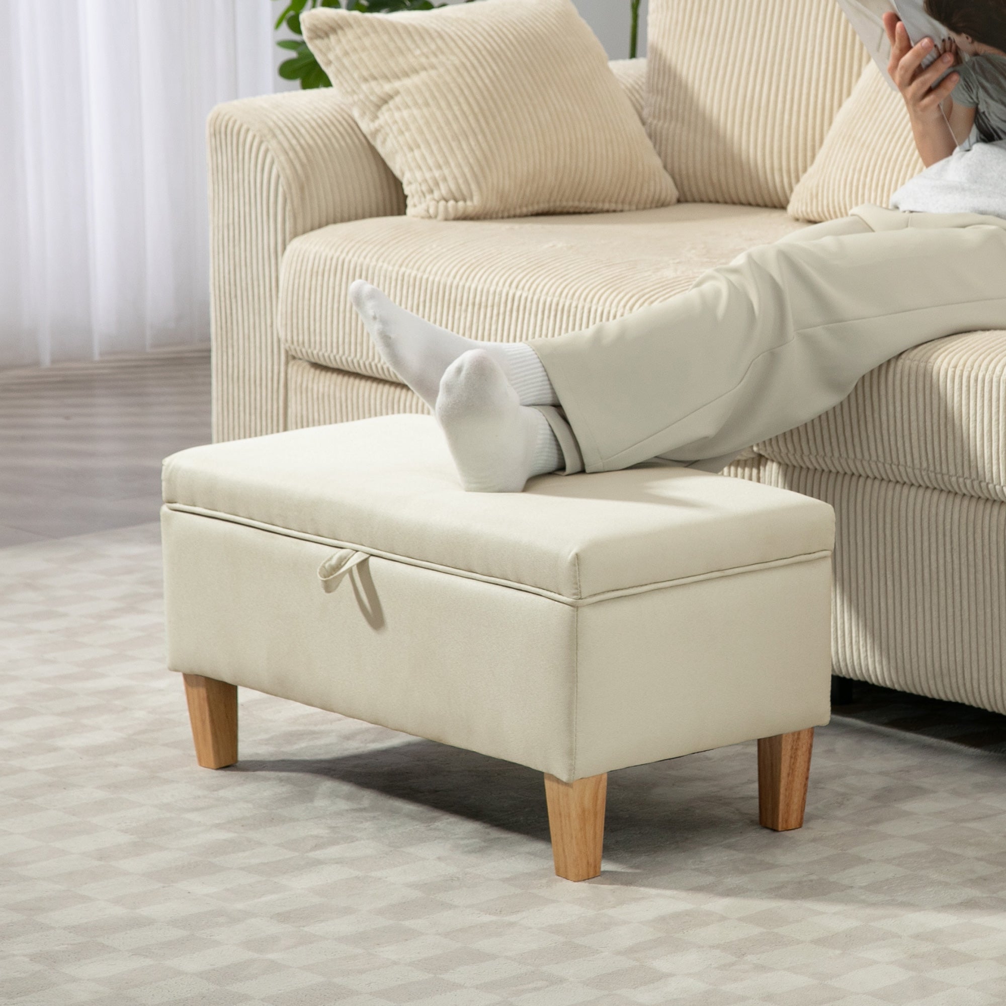 Cream-colored linen storage ottoman with wooden legs and fabric tie closure perfect for bed end seating and storage