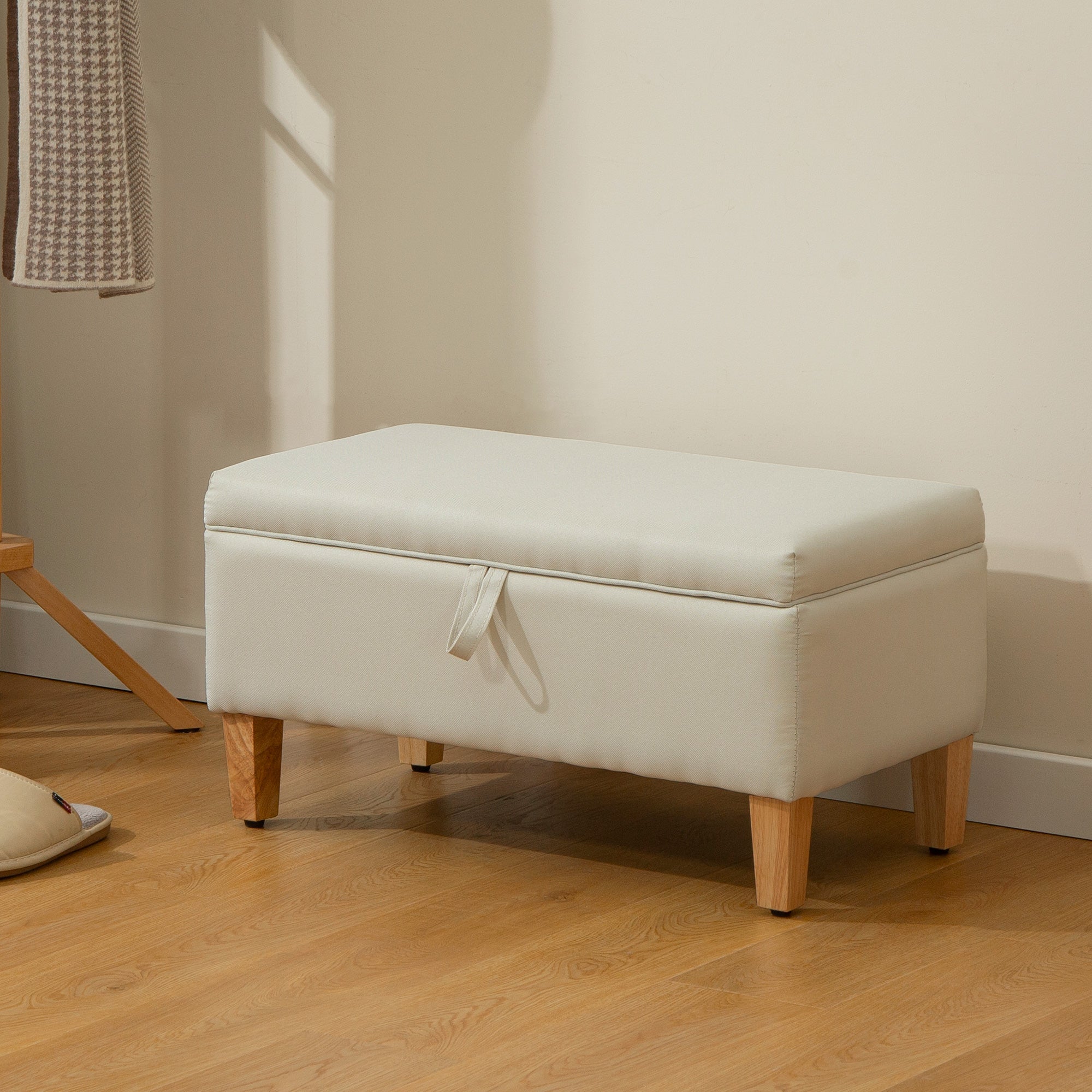 Cream-colored faux leather storage bench with fabric strap closure and rubberwood legs ideal for bed end seating