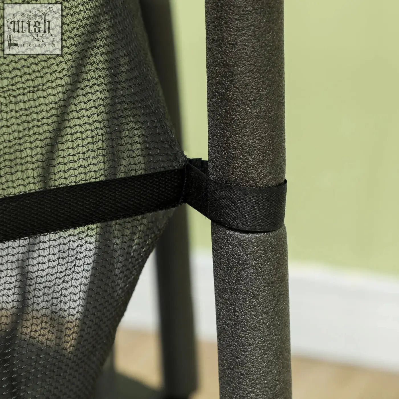 Black mesh netting with black fabric strap secured around a gray pole on homcom kids trampoline safety enclosure