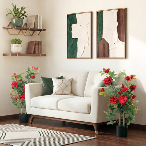 White upholstered sofa with dark wood legs and green beige pillows next to a red artificial rose tree set for indoor decor