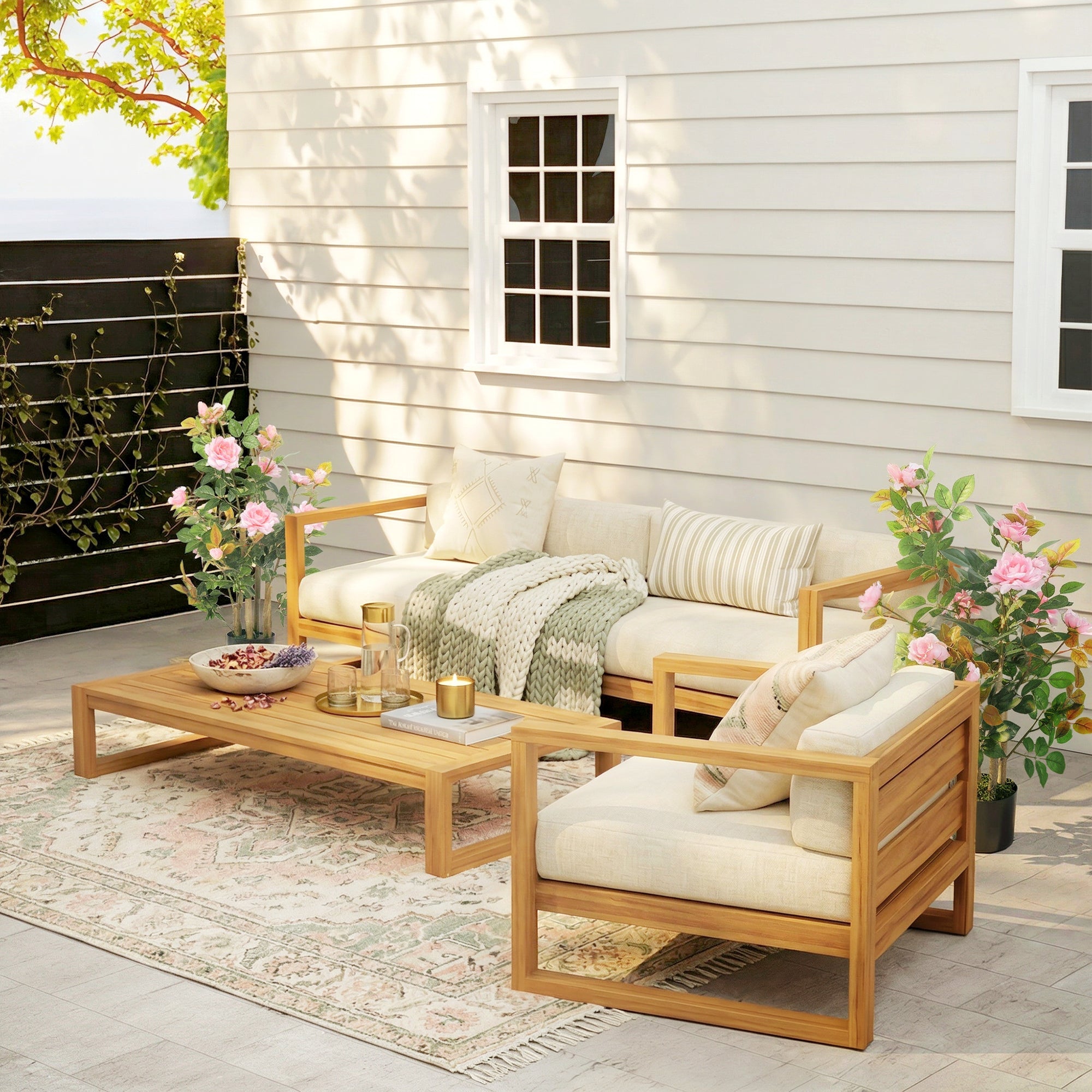 Light wood outdoor sectional sofa with cream cushions next to pink artificial rose tree set with silk leaves and flowers