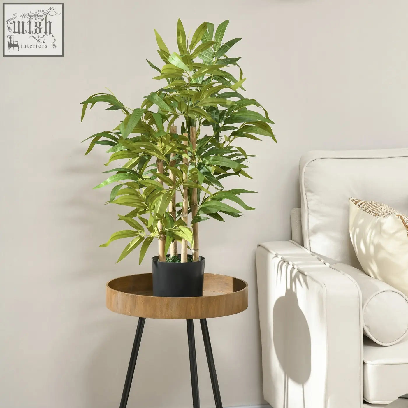 A lush green faux bamboo plant in a sleek black pot on a minimalist wooden side table for indoor decor