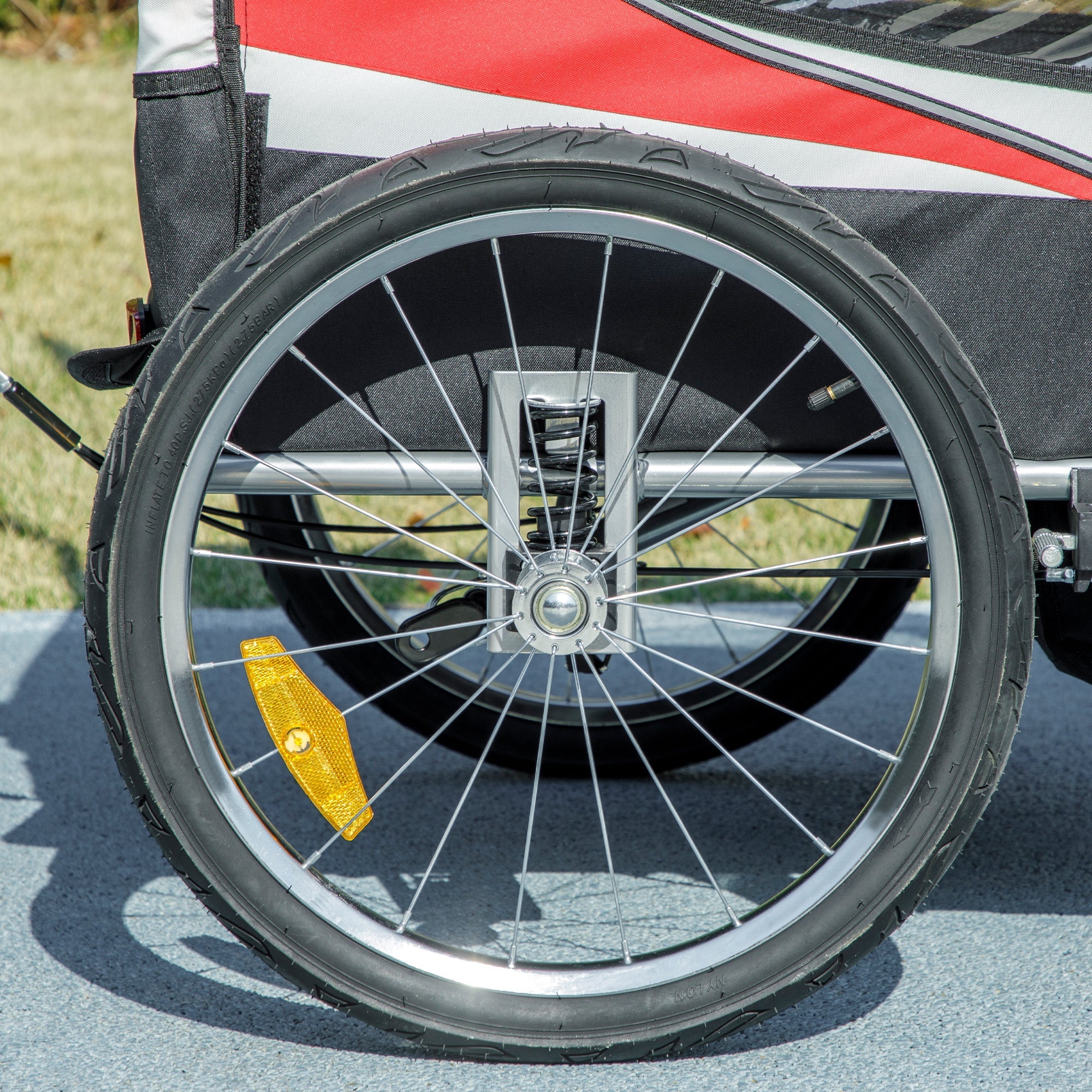 Black rubber tire with silver metal rim and yellow reflector on the baby bike trailer for safe riding and visibility