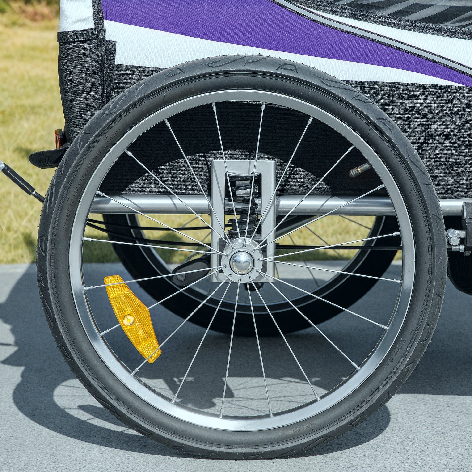 Silver-spoked wheel with black tire and yellow reflector on the purple homcom baby bike trailer steel frame back side