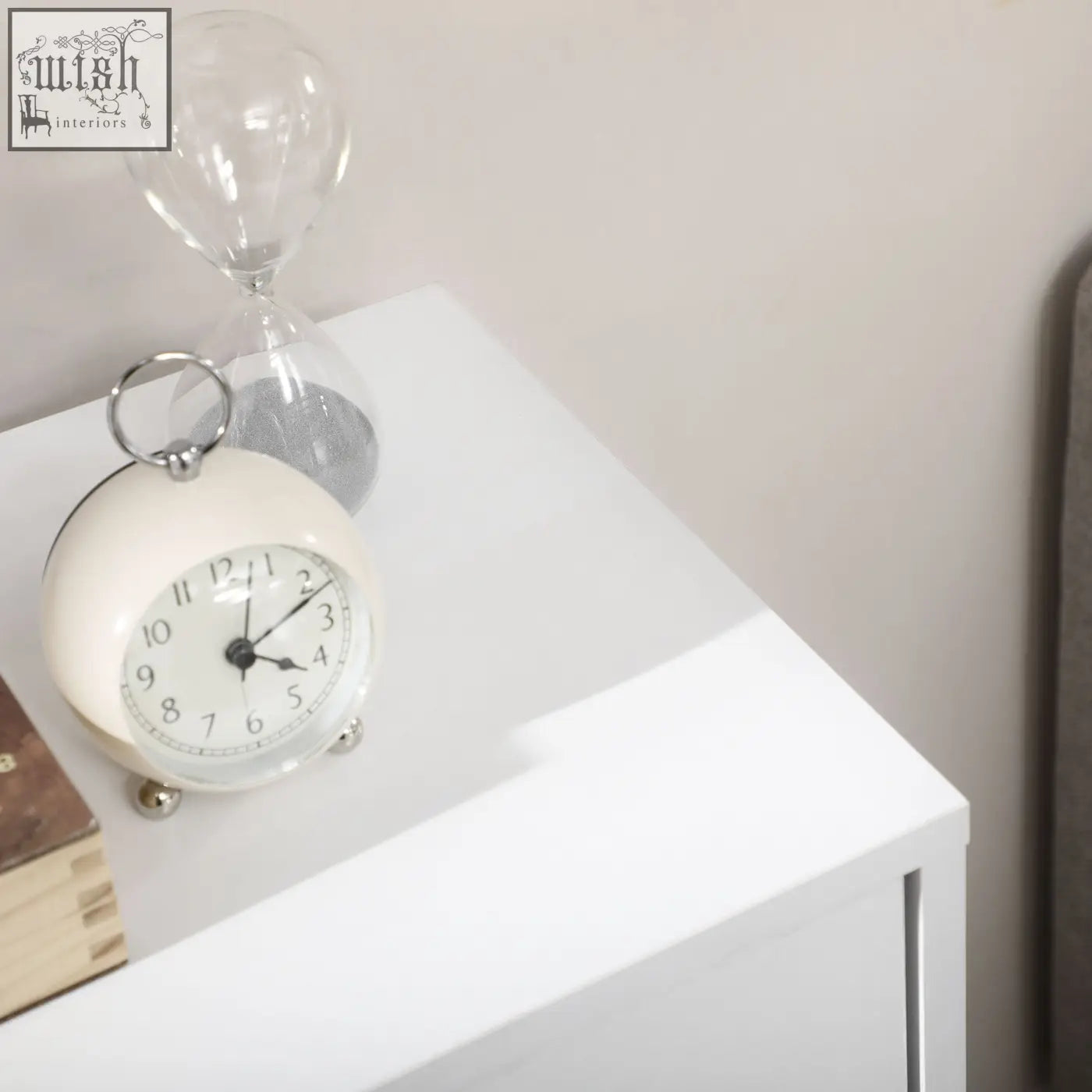 Cream-colored vintage alarm clock on top of white homcom bathroom freestanding two-tier cabinet with four drawers