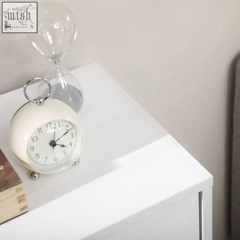 Cream-colored vintage alarm clock on top of white homcom bathroom freestanding two-tier cabinet with four drawers