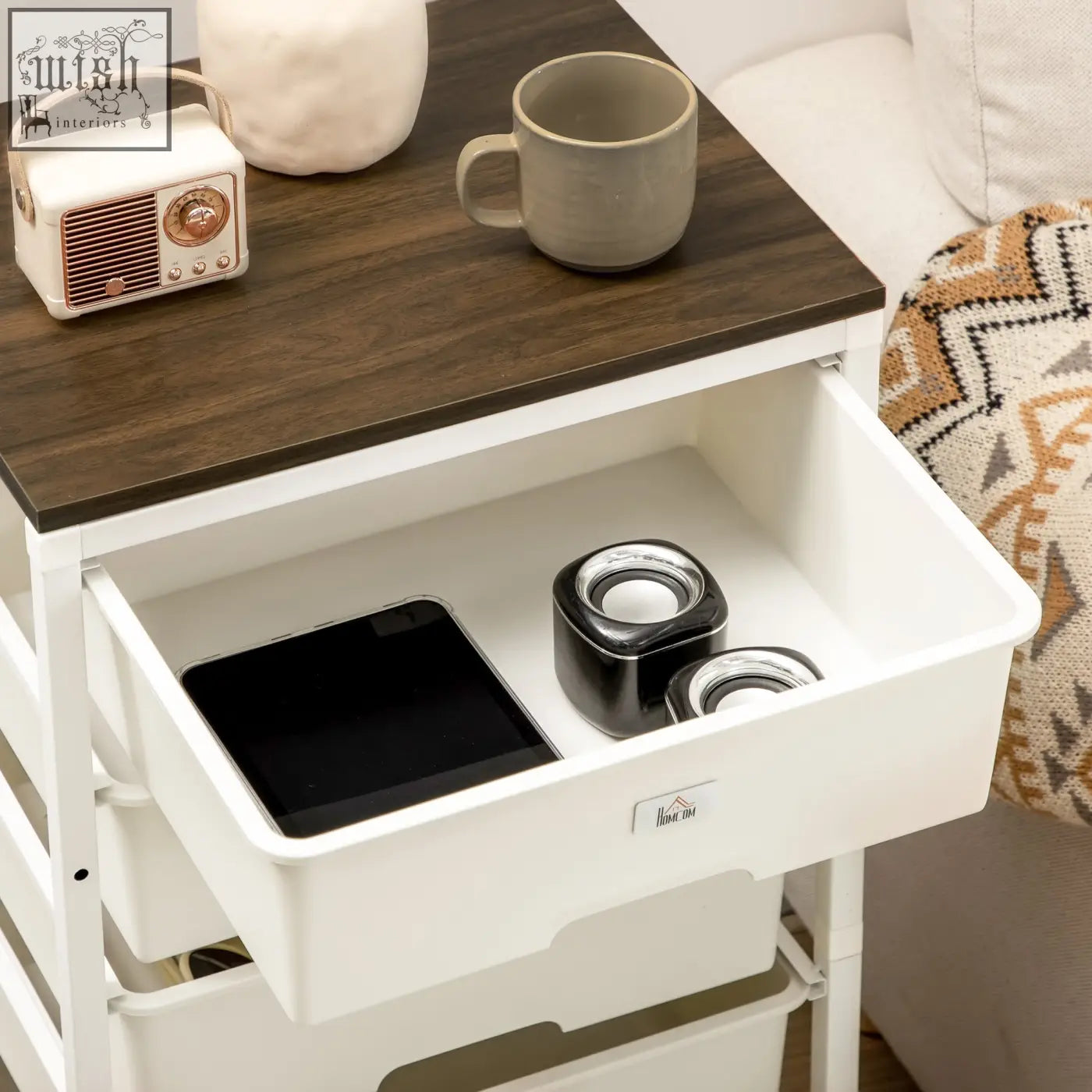 White plastic storage cart with dark wood top and steel frame features six drawers, one open with speakers and tablet inside