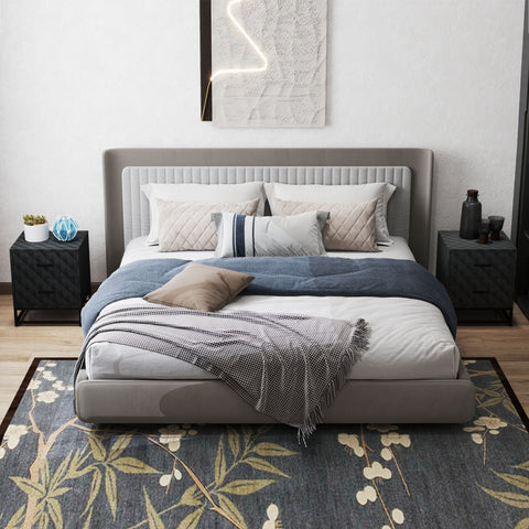Modern gray upholstered bed with tufted headboard and white linens next to black steel frame bedside table with drawers
