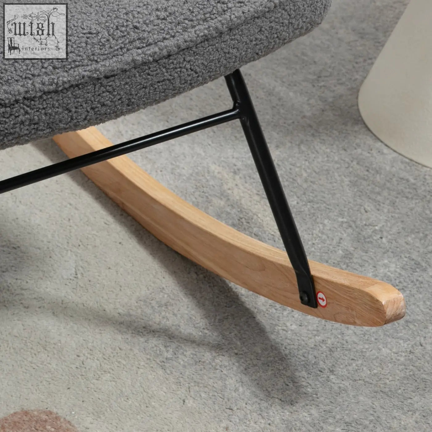 Gray textured fabric rocking chair with black metal frame and curved wooden base for gentle rocking in nursery