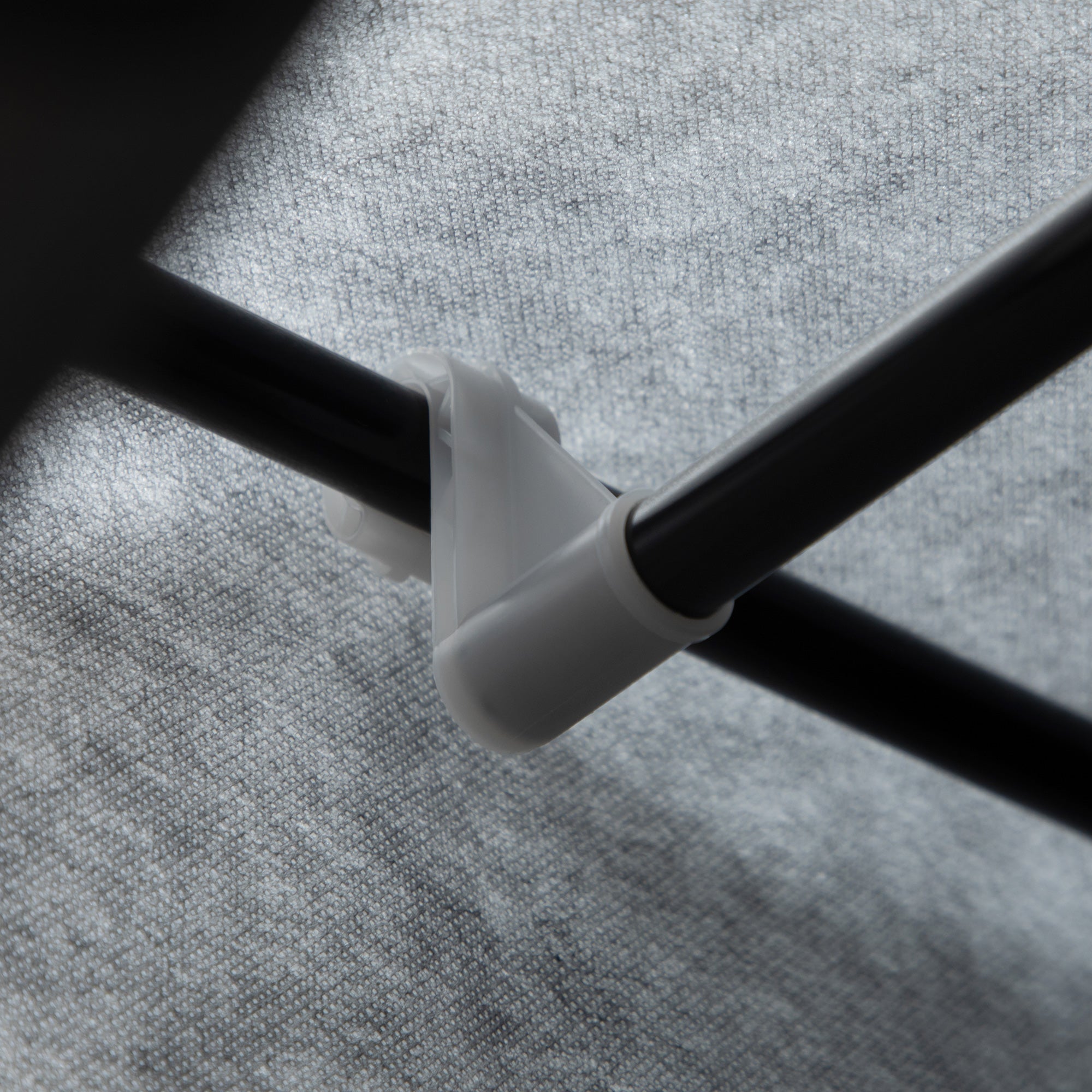 White plastic pipe clamp securing two black poles on the back of homcom fabric wardrobe with hanging rod and clothes storage