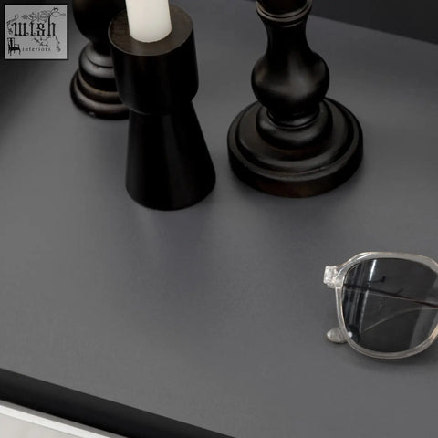 Clear-framed sunglasses rest on a gray surface in front of a high gloss grey shoe cabinet with white doors and open shelves