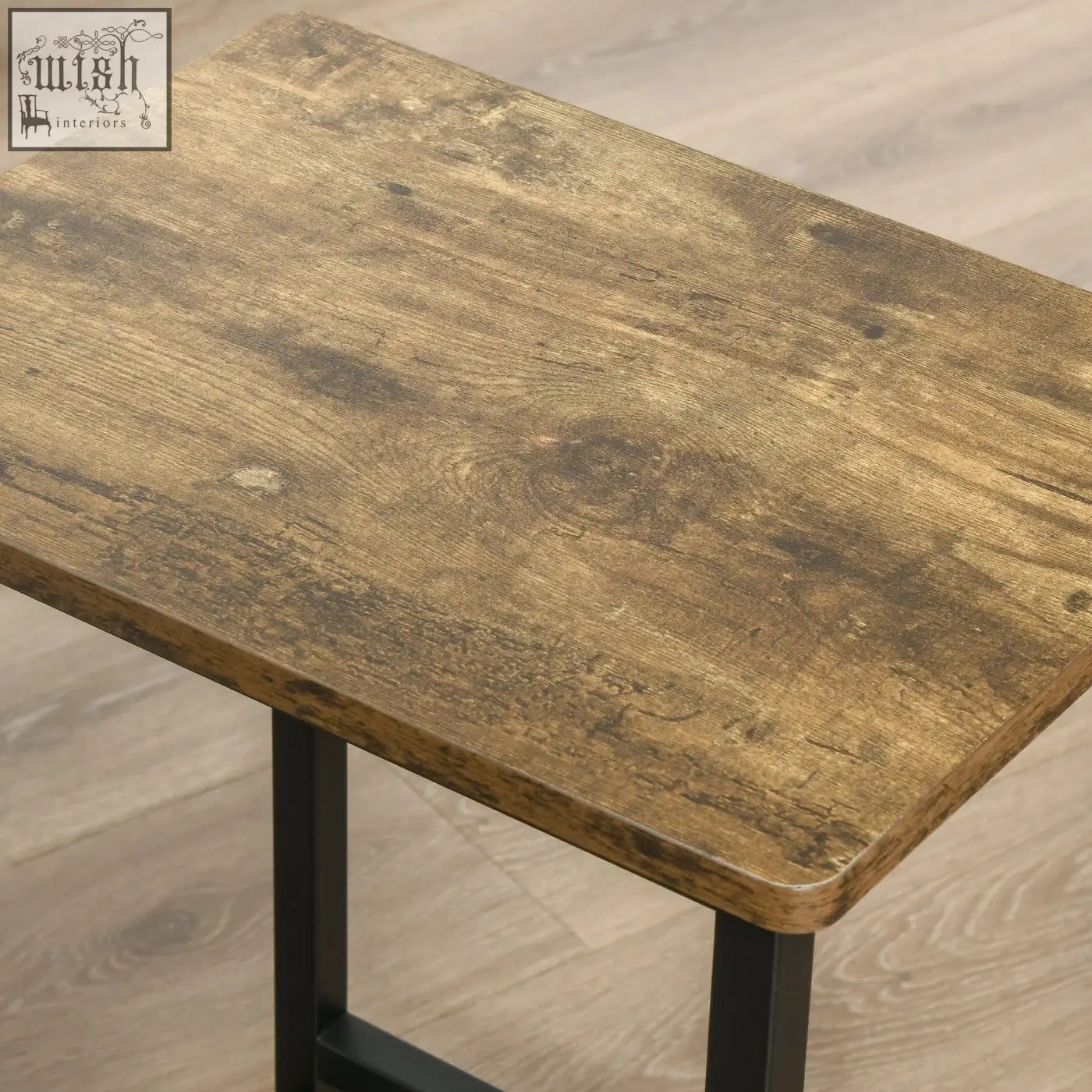 A rustic brown wooden table with a weathered finish and black metal legs paired with particle board seats bar stools