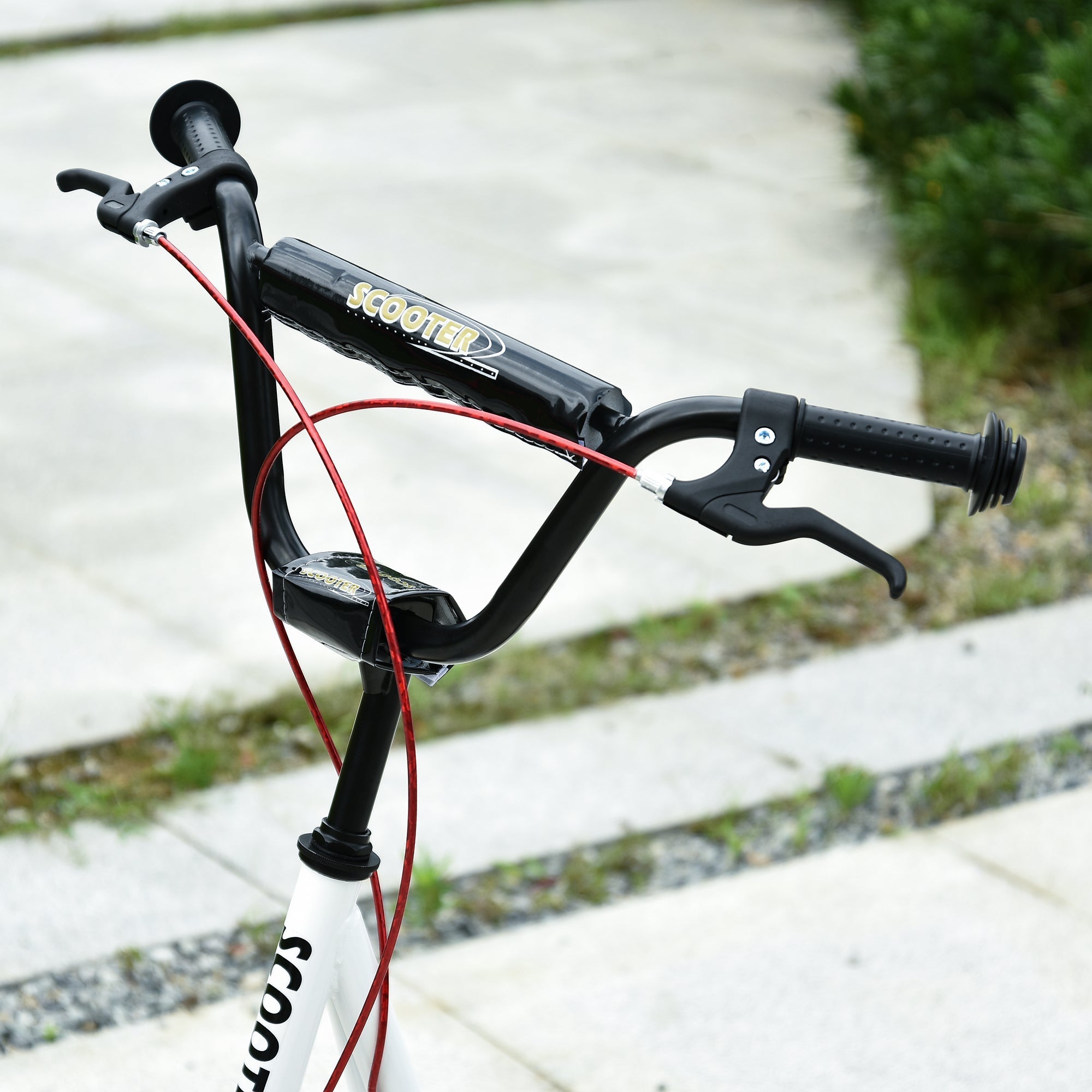 Black scooter handlebar with red brake cables and textured grips on white homcom kids scooter with rubber wheels