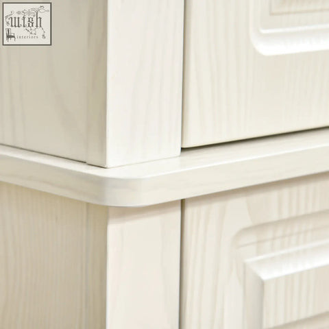 Cream-colored wooden dresser with subtle grain finish and raised panel drawers in white wood grain design