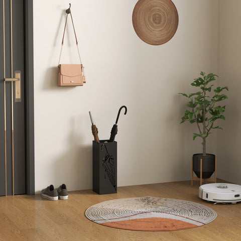 Beige crossbody bag with chain strap and gold hardware beside black metal umbrella stand with removable drip tray for umbrella storage