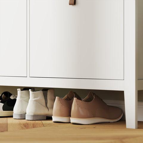 Beige leather lace-up shoes with white soles placed on top of a white homcom modern shoe cabinet with four flip drawers